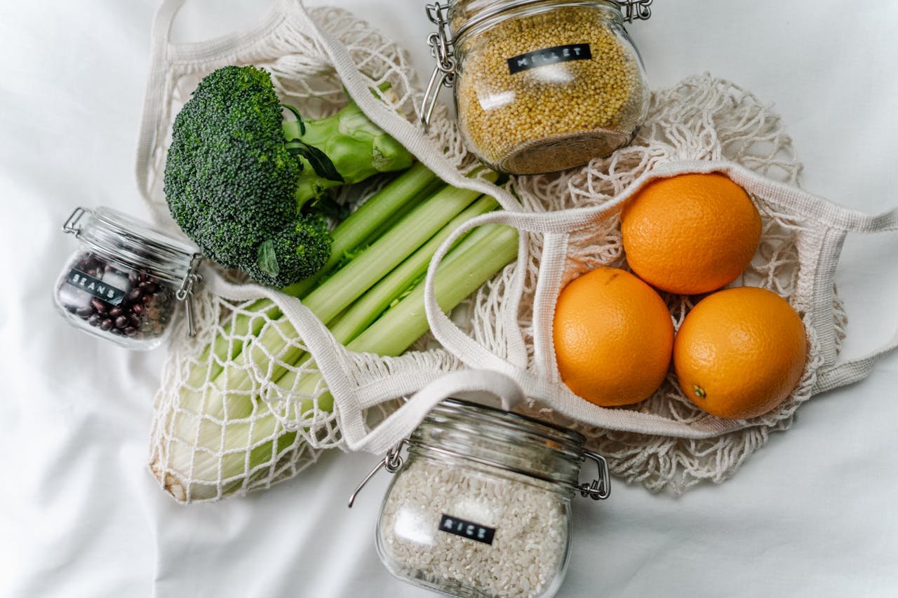 about-03 Overhead view of eco bags with broccoli, oranges, and grains in jars, promoting a zero-waste lifestyle.