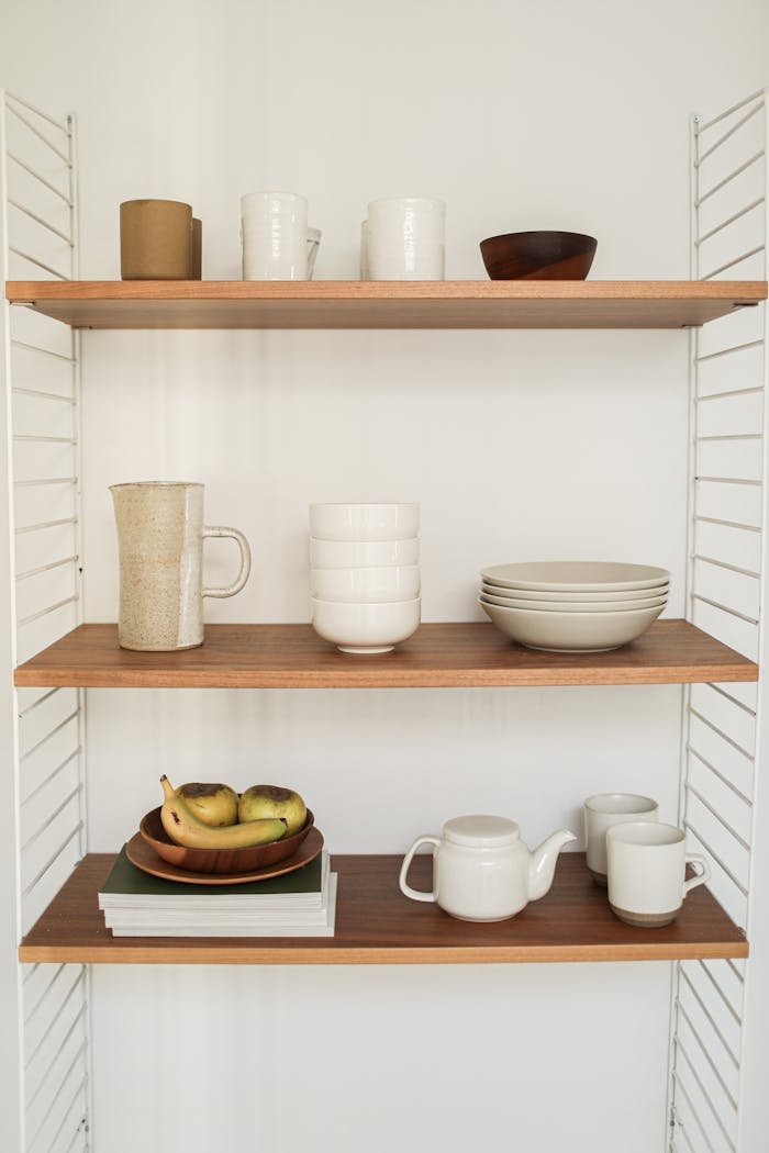 services-03 Stylish wooden shelves displaying ceramics including cups, bowls, teapot, and pitcher.